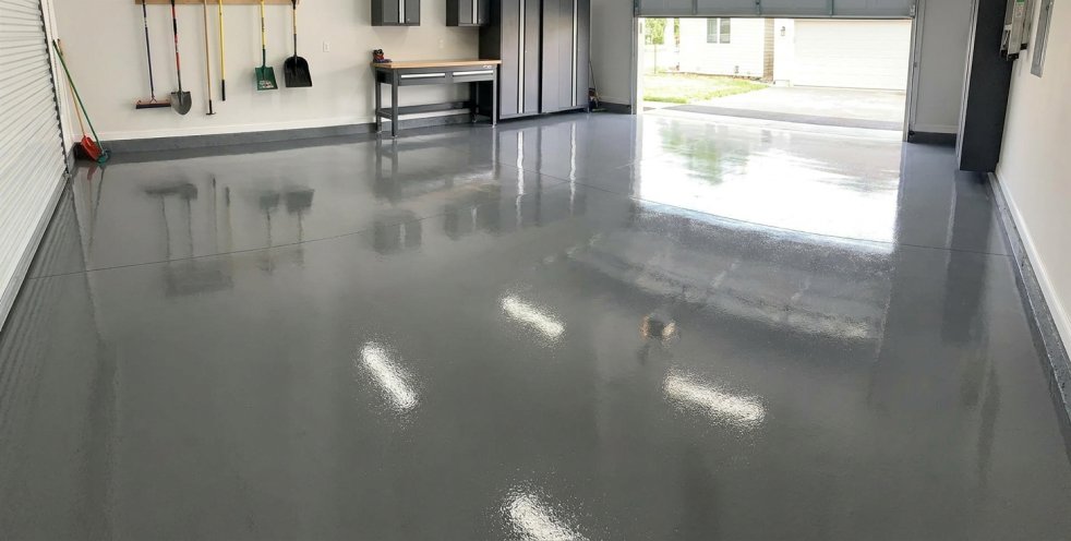 Glossy epoxy-coated garage floor with tools on the wall and an open garage door